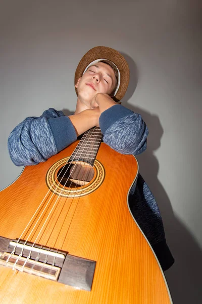 En pojke spelar gitarr på en grå bakgrund i studion, vidvinkel närbild foto. — Stockfoto