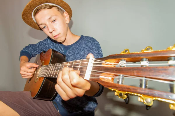 Un niño toca la guitarra sobre un fondo gris en el estudio, foto de primer plano de gran angular . —  Fotos de Stock