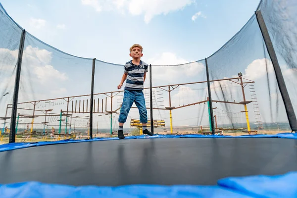Chłopiec skacze na trampolinie w parku rozrywki, wykonując różne akrobacje. — Zdjęcie stockowe