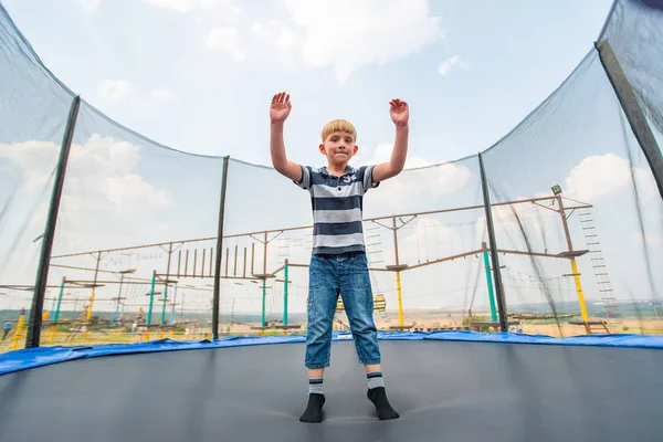 Chłopiec skacze na trampolinie w parku rozrywki, wykonując różne akrobacje. — Zdjęcie stockowe