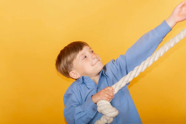 El niño se estira sobre una cuerda sobre un fondo amarillo, el concepto de lograr el éxito . — Foto de Stock