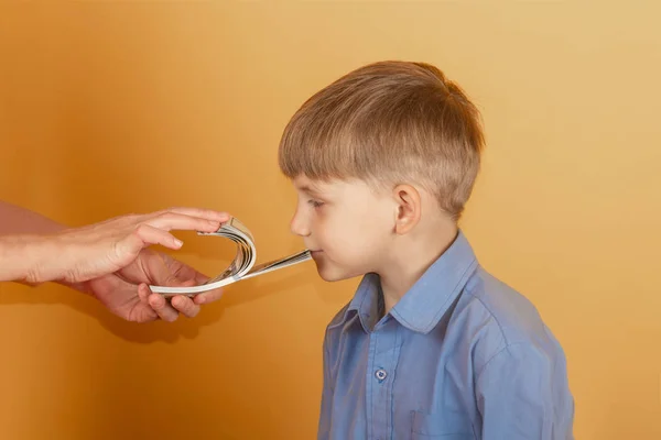 Pojken i den blå skjortan sträcker ut sin hand och tar dollar. — Stockfoto