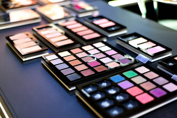 Exhibition of cosmetics in a boutique, eyeshadow on sale in a store. Colorful and gorgeous colors for professional makeup.
