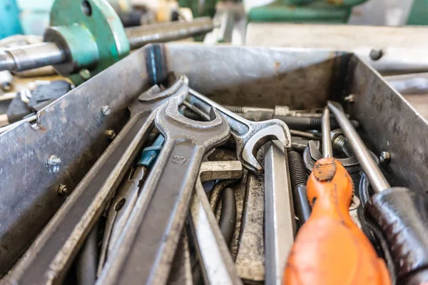 A set of working tools of a repairman's fitter, open-end wrenches and screwdrivers are in a metal box during the repair process.