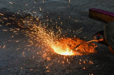 Üretimde bir gaz kesici, bir kaynakçı bir gaz kesici ile gereksiz metal kalıntıları kaldırır, kıvılcım farklı yönlere uçmak.