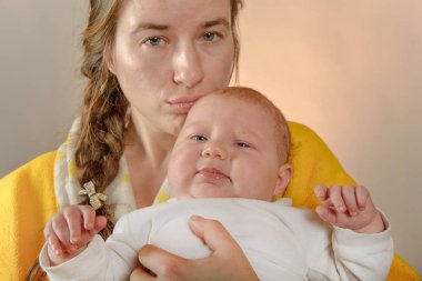 Anne kollarında bebek tutar ve stüdyoda kamera için pozlar, sevgi ve birlik kavramı ve sevdiklerinive küçük olanlar için bakım.