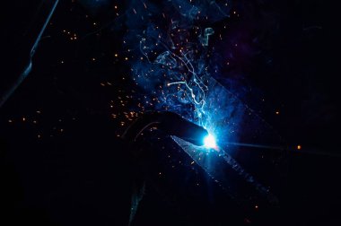Kaynakçı metal ürünlerden metal yapılar yapar ve bir kaynak ile bağlanır.