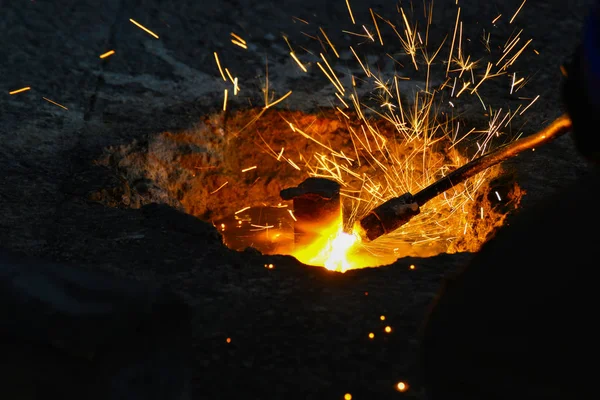 Een gassnijder in productie, een lasser verwijdert onnodige metaalresten met een gassnijder, vonken vliegen in verschillende richtingen. — Stockfoto