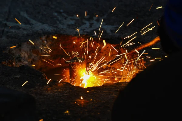 Een gassnijder in productie, een lasser verwijdert onnodige metaalresten met een gassnijder, vonken vliegen in verschillende richtingen. — Stockfoto