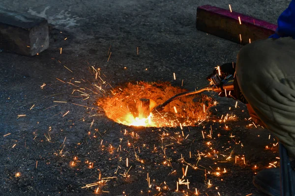 A gas cutter in production, a welder removes unnecessary metal residues with a gas cutter, sparks fly in different directions. — Stock Photo, Image