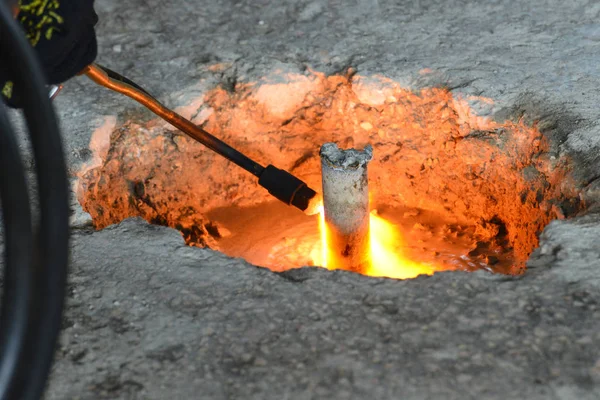 Een gassnijder in productie, een lasser verwijdert onnodige metaalresten met een gassnijder, vonken vliegen in verschillende richtingen. — Stockfoto