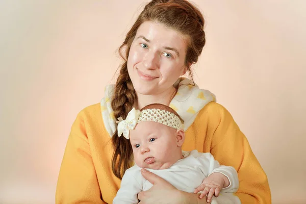 Maman tient le bébé dans ses bras et pose pour la caméra dans le studio, le concept d'amour et d'unité et de soins pour les proches et les plus jeunes . — Photo