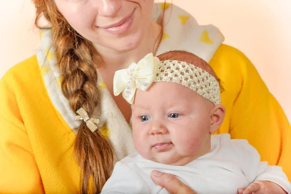 Mamma tiene il bambino tra le braccia e posa per la fotocamera in studio, il concetto di amore e unità e la cura per i propri cari e più giovani . — Foto Stock