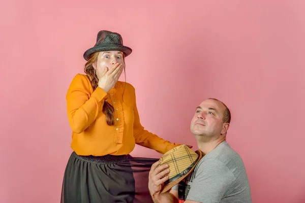 Un uomo e una donna in un cappello di paglia su uno sfondo rosso in posa per la fotocamera in studio . — Foto Stock