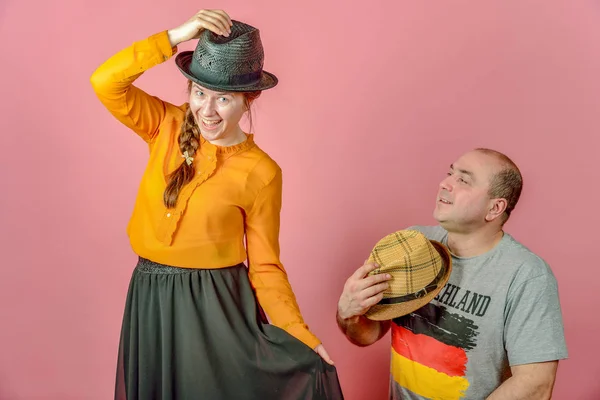 Un uomo e una donna in un cappello di paglia su uno sfondo rosso in posa per la fotocamera in studio . — Foto Stock