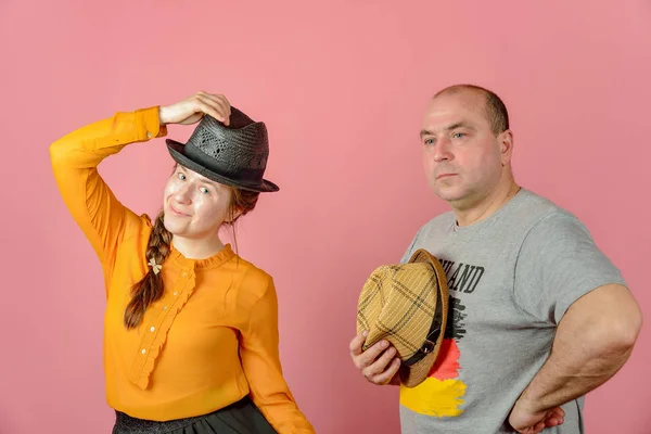 Un uomo e una donna in un cappello di paglia su uno sfondo rosso in posa per la fotocamera in studio . — Foto Stock