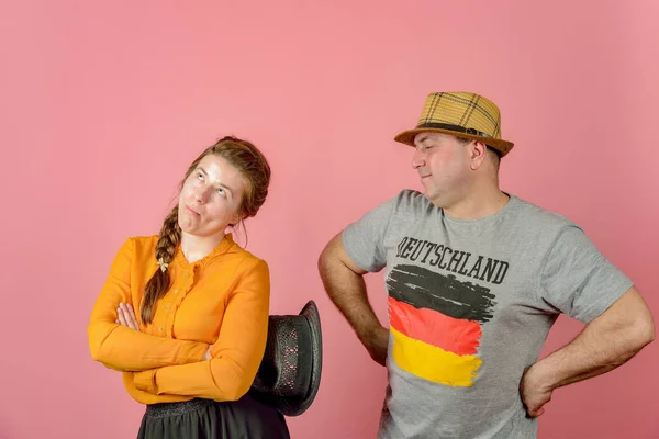 Un uomo e una donna in un cappello di paglia su uno sfondo rosso in posa per la fotocamera in studio . — Foto Stock