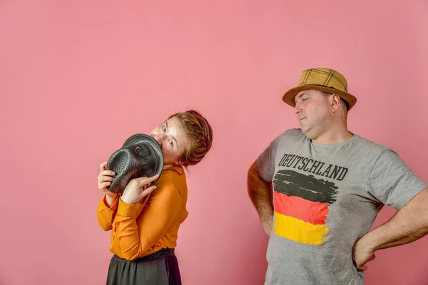 Un uomo e una donna in un cappello di paglia su uno sfondo rosso in posa per la fotocamera in studio . — Foto Stock