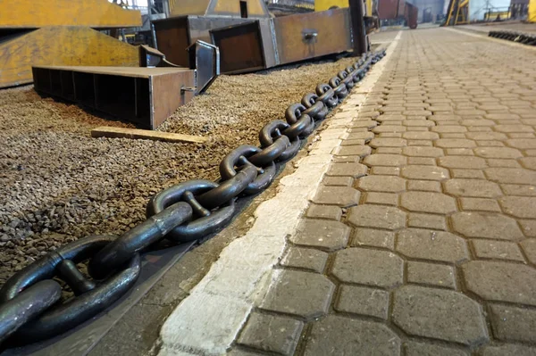 A large and long chain lies in the passage in the workshop.