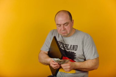 Sarı bir arka plan üzerinde bir dizüstü bilgisayar ve para ile Neşeli adam.