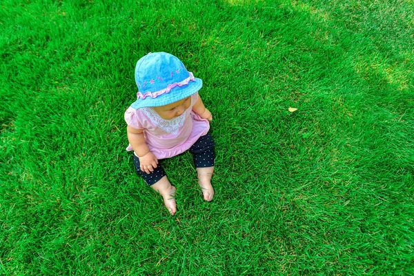 Vista superior de uma criança sentada na grama verde . — Fotografia de Stock