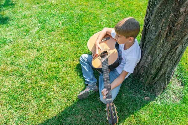 El niño toca la guitarra en la naturaleza, vista superior . —  Fotos de Stock