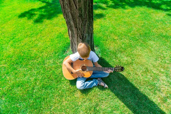 El niño toca la guitarra en la naturaleza, vista superior . —  Fotos de Stock