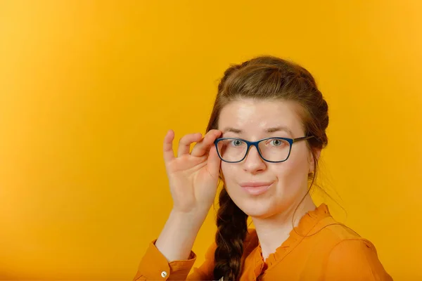 Fille avec des lunettes regardant la caméra sur un fond jaune . — Photo