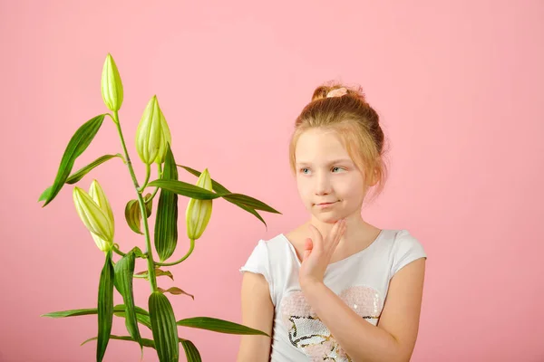 Modieuze en glamoureuze meisje met een bloem in de studio op een roze achtergrond. — Stockfoto