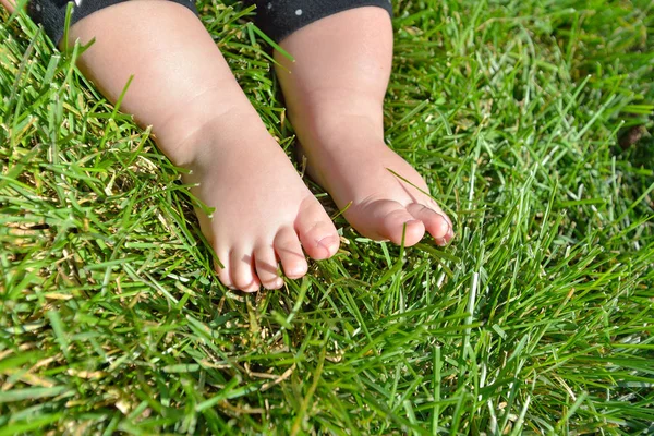 Malé dítě na trávě, dětské nohy na zelené trávě v parku. — Stock fotografie