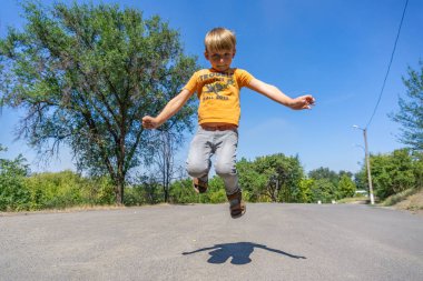Neşeli ve mutlu çocuk yolda atlıyor.