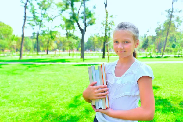 Portré egy lány tankönyvek a parkban, a lány megy osztályok tanulmányozása. — Stock Fotó