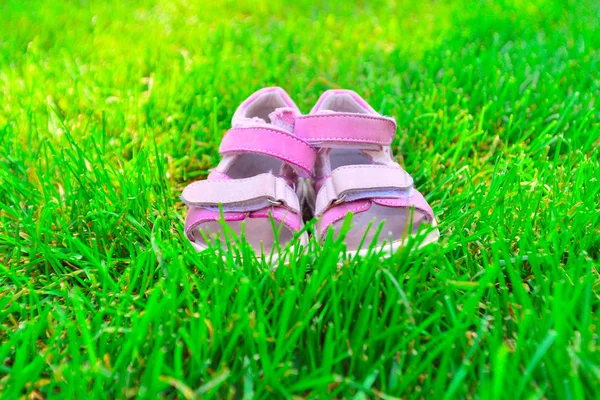 Pink gyermekszandál a zöld füvön a parkban. — Stock Fotó