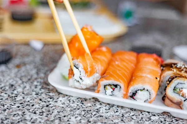 Sushi in a restaurant, Asian national seafood, a set of rolls of fish food with Chinese chopsticks.