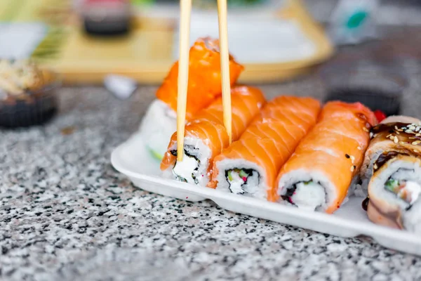 Sushi in a restaurant, Asian national seafood, a set of rolls of fish food with Chinese chopsticks.