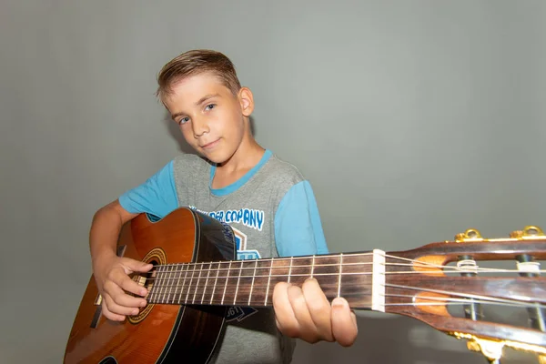 Um menino toca violão, foto de grande ângulo no estúdio de uma criança musical . — Fotografia de Stock