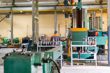 Bir cnc makinesinin arkasındaki frezeleme makinesi operatörü, üretim için bir parçayı ortaya çıkarır.