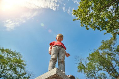 Bulutlu bir gökyüzüne karşı bir tepede bir çocuk, alt görünümü.