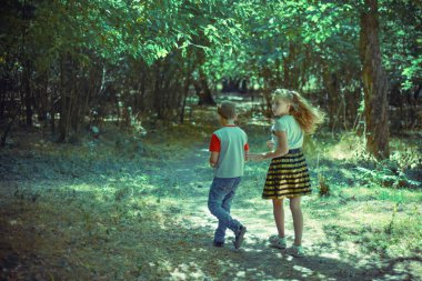 Bir erkek ve bir kız ormanda bir yol boyunca yürümek ve geriye bakmak