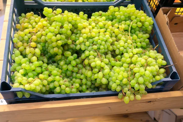 Raisins parfumés et juteux sur le comptoir et dans un récipient en bois dans le magasin . — Photo