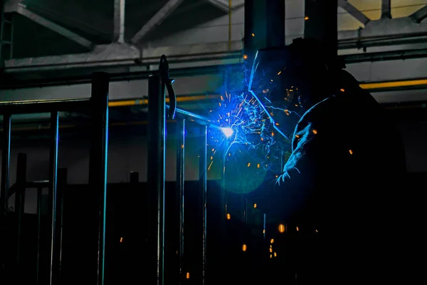 The welder makes the metalwork, connecting by welding, sparks fly along the sides. — Stock Photo, Image