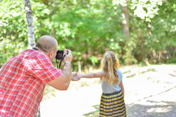 Un hombre fotografía a una chica caminando por el bosque . — Foto de Stock