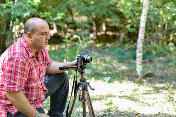 一名男性摄影师控制公园三脚架上的相机. — 图库照片