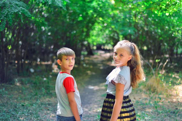 Un niño y una niña caminan por un sendero en el bosque y miran hacia atrás — Foto de Stock
