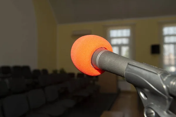 Un micrófono en un soporte en una habitación vacía con sillas sin personas . —  Fotos de Stock