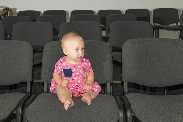 Una niña se sienta en una silla en el pasillo con un micrófono en las manos . — Foto de Stock