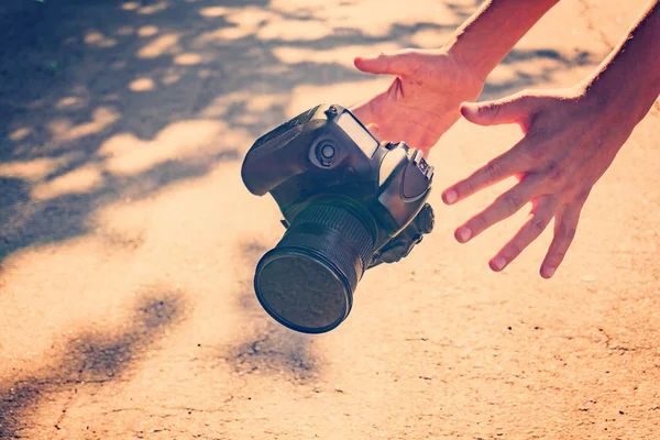 De fotograaf zette de camera en vangt het met zijn handen, de camera valt op het asfalt. — Stockfoto