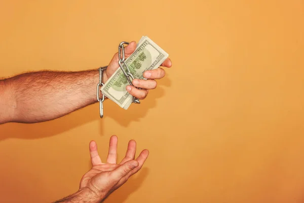 La mano del hombre está envuelta en una cadena, sostiene dólares. Concepto de dependencia monetaria y financiera . — Foto de Stock