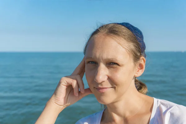 Retrato de una niña en una bufanda azul, primer plano sobre un fondo del mar . — Foto de Stock