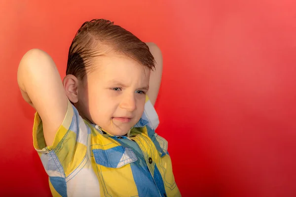 Chico enojado en una camisa a cuadros sobre un fondo rojo —  Fotos de Stock